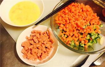将火腿、红萝卜和黄瓜切丁，鸡蛋打散，加一点水后继续打散，洋葱头切丝切丁都可；