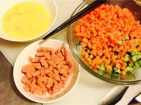 将火腿、红萝卜和黄瓜切丁，鸡蛋打散，加一点水后继续打散，洋葱头切丝切丁都可；