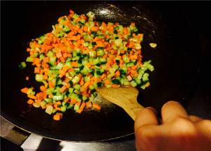 再放入火腿丁，翻炒片刻后放入红萝卜丁，把红萝卜香气炒出；