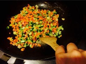 再放入火腿丁，翻炒片刻后放入红萝卜丁，把红萝卜香气炒出；