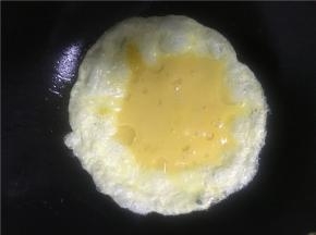 倒入打散的鸡蛋，不要急着翻炒待鸡蛋，先做成两面金黄的鸡蛋饼（刚开始先不急着炒碎鸡蛋而是做成鸡蛋饼，是因为蛋液由于空气被加热在鸡蛋饼内部形成气泡的作用，使鸡蛋内部结构比较疏松，可以达到外部金黄内部滑嫩的效果，吃起来也略有蓬松感）