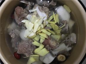 将牛肉带汤一起倒入炖锅中，加入蒜片、姜片和盐