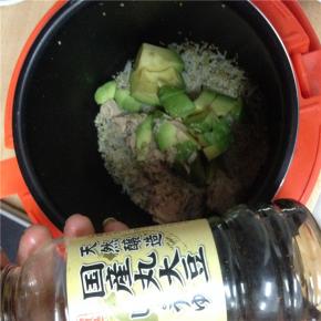 待米饭蒸熟后，将牛油果放入锅中，并舀出适量金枪鱼放入锅中，加少许酱油，拌匀。