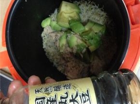 待米饭蒸熟后，将牛油果放入锅中，并舀出适量金枪鱼放入锅中，加少许酱油，拌匀。