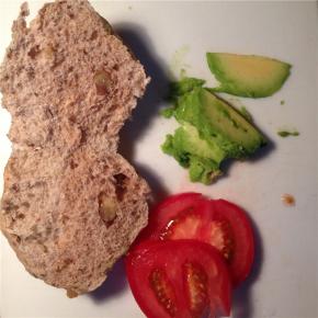 将牛油果和西红柿切片，并将餐包从中间切成两半。