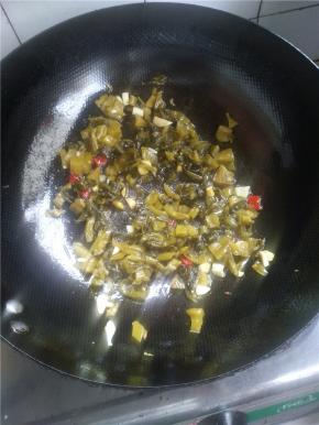 将锅内多余的油倒出，放入姜蒜酸菜辣椒炒香。