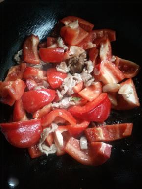 锅内放油下蒜瓣，有香味后马上下肉片，肉片炒至变色后下甜椒。