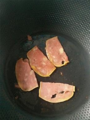 热锅凉油，油热之后将切片的火腿放入锅中煎1分钟