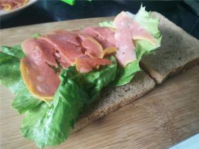 将生菜平铺的放在面包片上，煎好的火腿片放在生菜上