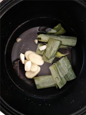 电饭煲内加入水，然后加入葱叶及剩余的姜片和蒜，熬制高汤。等炒锅里的汤煮开熬制5分钟左右倒入电饭煲内继续按煮饭键熬制。