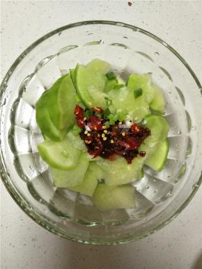 削好的萝卜上放入调味品，最重要的是一定要用黄豆酱，其次加入耗油、盐以及浇上香油提味，最后撒入葱花和干辣椒。