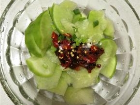 削好的萝卜上放入调味品，最重要的是一定要用黄豆酱，其次加入耗油、盐以及浇上香油提味，最后撒入葱花和干辣椒。