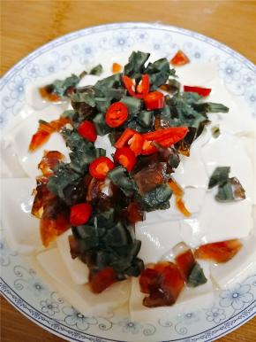 内酯豆腐切成片装盘，由于豆腐比较软，所以切的时候一定小心不要切刀手，皮蛋切丁。