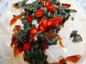内酯豆腐切成片装盘，由于豆腐比较软，所以切的时候一定小心不要切刀手，皮蛋切丁。