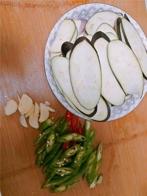 茄子切成椭圆片，蒜切片，青椒切碎。