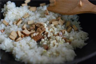 接着放鸡蛋干、蒜蓉进去翻炒，加一勺薄盐生抽翻炒上色