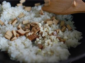 接着放鸡蛋干、蒜蓉进去翻炒，加一勺薄盐生抽翻炒上色