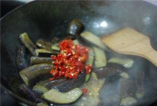 茄子变软后加入剁椒和蒜翻炒，最后加盐、鸡精调味