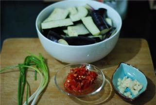 准备食材，三根细茄子，先切段，约一指长，再对半切，然后放盐水里浸泡10-20分钟（然后盐水倒掉，再用清水冲一遍）；剁椒一勺、蒜切碎