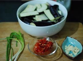 准备食材，三根细茄子，先切段，约一指长，再对半切，然后放盐水里浸泡10-20分钟（然后盐水倒掉，再用清水冲一遍）；剁椒一勺、蒜切碎