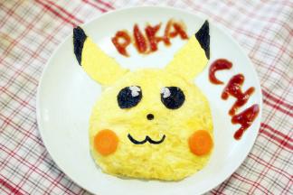 海苔用厨房剪刀剪出眼睛、鼻子和嘴巴。胡萝卜切片作为腮红，将另一个蛋皮剪成耳朵的形状，耳朵的顶部沾上海苔作为装饰，将所有的表情摆好，可爱的皮卡丘就做好了