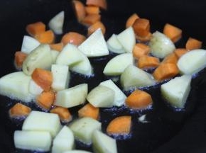 锅内放油，油热之后倒入胡萝卜和土豆翻炒至表面成金黄色，盛出控油