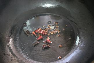 锅内留底油，放入花椒和干辣椒小火炒出香味，放入葱段
