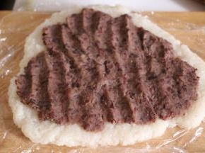 最后，将炒好的豆沙馅平铺在糯米皮上，卷起来，用手裹紧，撕掉保鲜膜，切成块即可