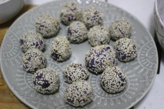 紫薯球表面沾上薄薄的一层水，放到芝麻里滚一下