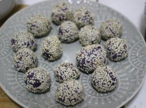 紫薯球表面沾上薄薄的一层水，放到芝麻里滚一下