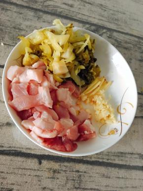 酸菜洗净切细，猪肉切块，切好姜丝，剁蒜泥