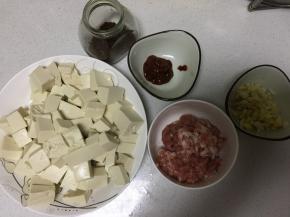 将豆腐洗净切块，用开水焯2分钟，开水中要加入盐，去豆腥味，姜蒜切沫，准备好豆瓣酱、花椒面，肉馅儿