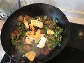 在锅内加入煎熟的鸡蛋块，大火翻炒几下，即可出锅
