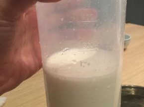 将步骤一中的吉利丁粉液倒入煮融的牛奶液中，搅拌均匀后过筛，倒回量杯