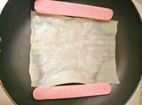 锅内倒少许油，放入冷面和肠，烤肠可以提前煎一下，放入冷面后，在冷面上刷些水。