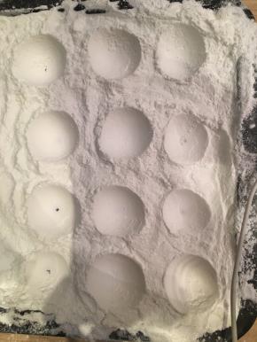 在烤盘上铺一层熟的玉米淀粉（可以用烤箱烤熟生的玉米淀粉），用鸡蛋压出一个个圆坑。