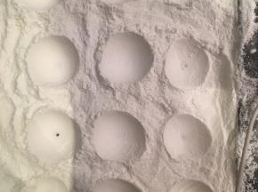 在烤盘上铺一层熟的玉米淀粉（可以用烤箱烤熟生的玉米淀粉），用鸡蛋压出一个个圆坑。
