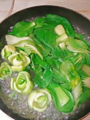 油菜焯水，去除草酸，水里加少许盐，使油菜更绿，煮好的油菜菜根用来摆盘，菜叶一会和香菇一起炒。