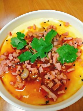 取出后，放入火腿丁，并倒入少许蒸鱼豉油，或者放入香油都行。