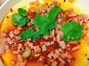 取出后，放入火腿丁，并倒入少许蒸鱼豉油，或者放入香油都行。