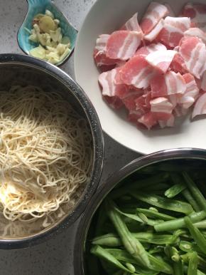准备材料，五花肉切片，豆角斜切成段，湿面条切成约15厘米长的短面条，这样最后和菜混合的时候就不会因为面条太长而打结，更容易搅拌均匀。葱姜蒜切好备用。