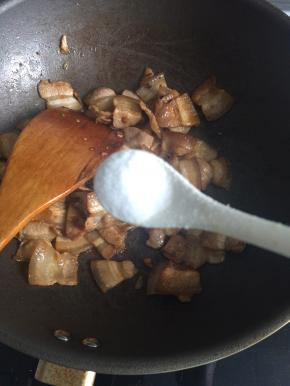 取一半的葱姜蒜起锅爆香，下入五花肉片煸炒至肉片发白出油后，加入老抽、盐调味，翻炒均匀即可出锅备用，肉不需要炒太熟，等下还要和豆角一起炖。