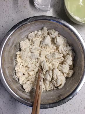 面粉放在盆里，一边加开水一边搅拌成雪花状。