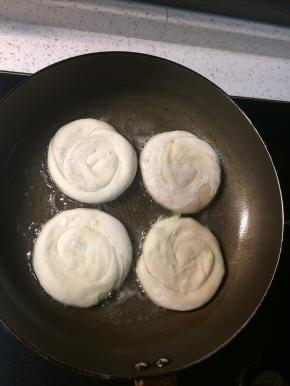 平底锅内加入能覆盖锅底约2-3mm深的油，将之前盘好的小饼用手压扁，用擀面杖轻轻擀至自己喜欢的厚度，放入锅里小火煎至两面金黄即可。