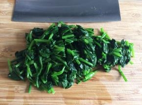 将菠菜从冷水中捞出，轻轻挤去水分，切成小段。