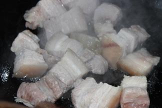 放入料酒和姜片焯水两分钟，油锅坐热，放入老冰糖，翻炒焯过水的肉块至表面微微变色