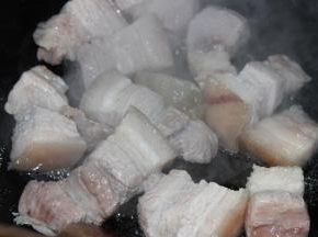 放入料酒和姜片焯水两分钟，油锅坐热，放入老冰糖，翻炒焯过水的肉块至表面微微变色