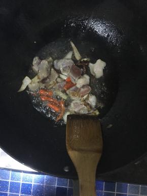 锅内放油，倒入调料炒香。并倒入肉进行翻炒, 肉炒变色后加入土豆豆角翻炒。