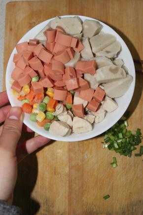 将墨鱼丸两次对切成丁，西红柿切丁，胡萝卜切丁，火腿肠切丁，小葱切粒，豌豆，玉米粒备好待用