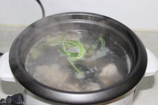将焯过水的排骨放入电饭煲内，加入新的姜片和葱，加入热开水，烧开后滤沫煮半小时
